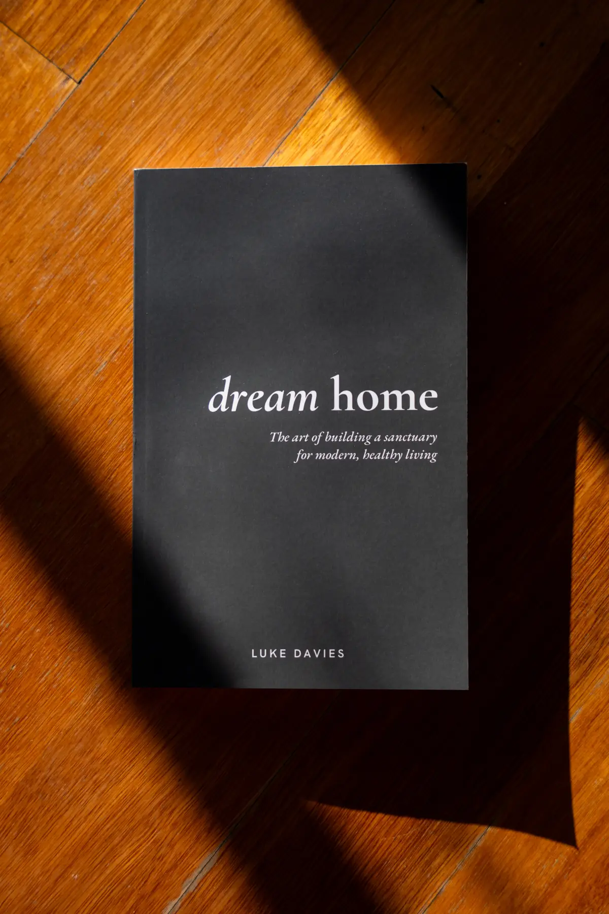 The Dream Home paperback lying on a timber floor in afternoon light